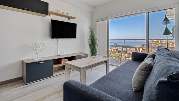 A modern living room with a sofa, TV, and a balcony with a view. - Casa Martin - Sea Views (Torremolinos)