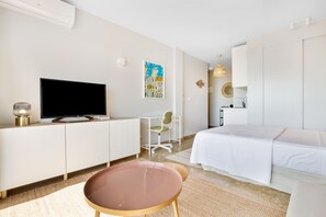 A hotel room with a bed, a TV, a desk, and a chair.