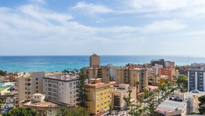 Un paisaje urbano costero con rascacielos, cielo despejado y el océano al fondo.