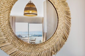 A circular woven mirror with a hanging light fixture above it.