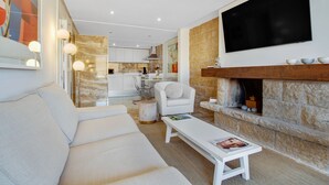Una sala de estar moderna con un sofá, una mesa de centro, una chimenea y una cocina al fondo.