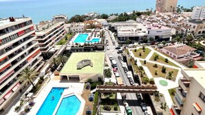 Un hotel con varias piscinas, una cancha de tenis y vistas al mar.