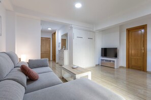 A modern living room with a grey sofa, a coffee table, a TV, and wooden doors.