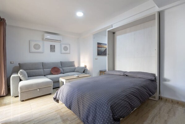 A modern bedroom with a bed, a sofa, and a small table.