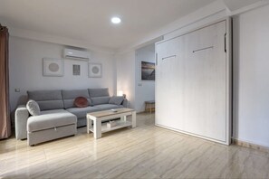 A modern living room with a grey sofa, a white coffee table, and a large wardrobe.