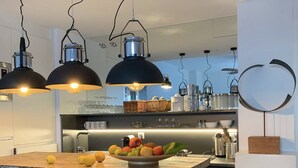 A modern kitchen with a wooden island, pendant lights, and a fruit bowl. - Casa Torre - Sea Views (Torremolinos)
