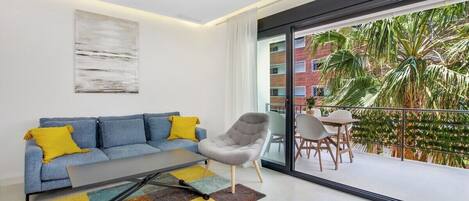Una sala de estar moderna con un sofá azul, un sillón gris y una alfombra colorida.