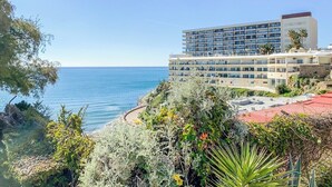 Um hotel à beira-mar com vários andares, varandas e vista para o mar.