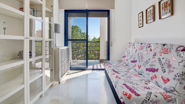 Un salon moderne avec un canapé, une bibliothèque et un balcon offrant une vue agréable.