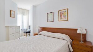 Une chambre d’hôtel avec un lit, un bureau, une chaise et deux œuvres d’art encadrées accrochées au mur.