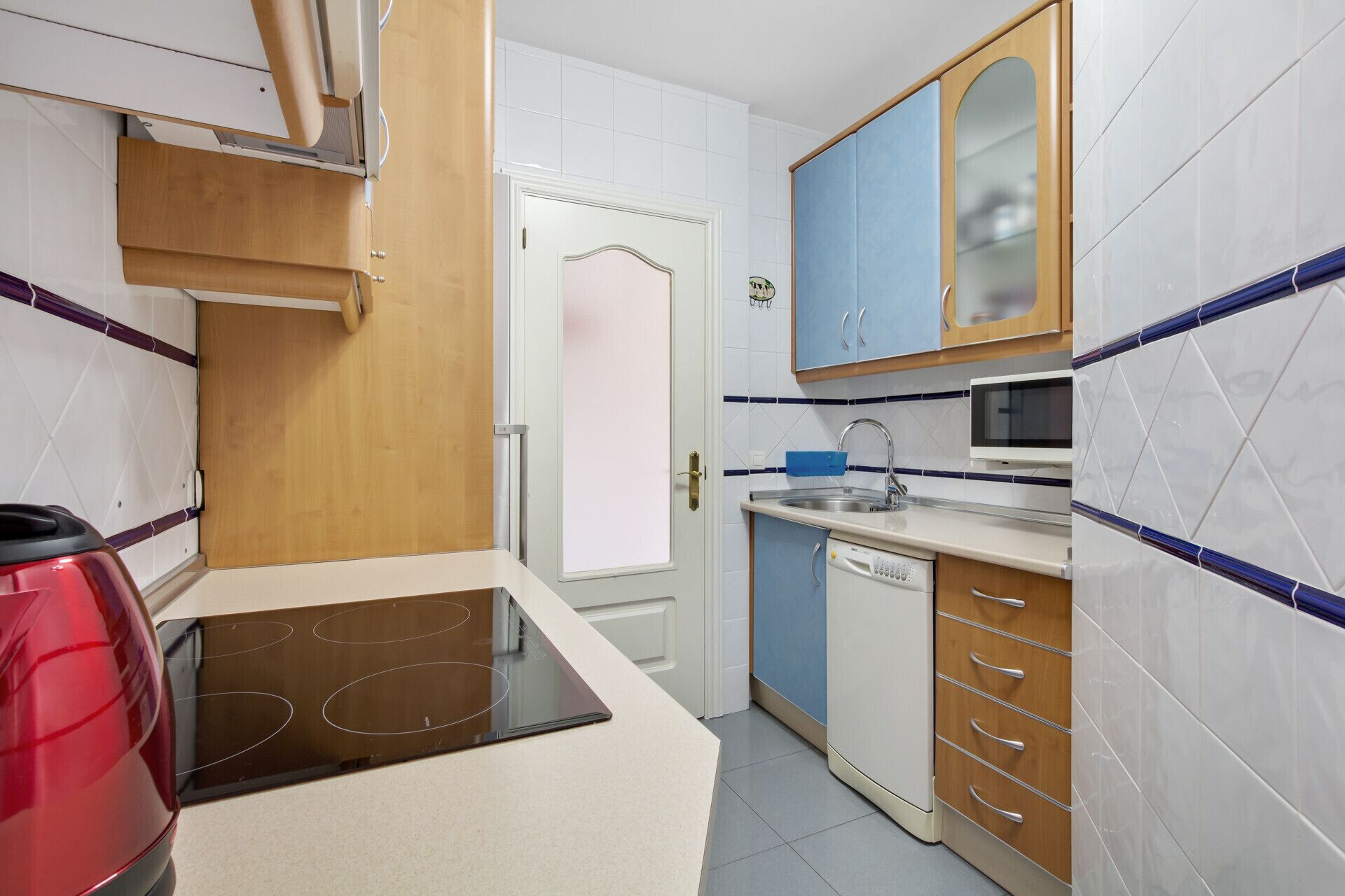 Una cocina compacta con microondas, lavamanos y armarios de madera.