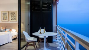 A balcony with a white table and chairs, two bottles of wine, and a bed with a white headboard. - Casa Alejandro - Sea Views (Torremolinos)