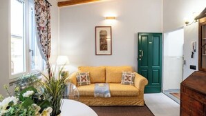 A living room with a sofa, a green door, and a framed picture on the wall. - Pratellino Florence Apartment (Firenze)