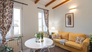 A cozy living room with a round table, a sofa, and a framed picture on the wall. - Pratellino Florence Apartment (Firenze)