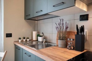 Une cuisine moderne dotée d’un plan de travail en bois, d’un évier en acier inoxydable et de meubles de couleur turquoise.