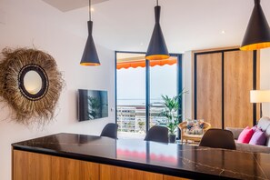 Una cocina moderna con encimera de mármol, lámparas colgantes negras y vistas de la ciudad a través de amplios ventanales.