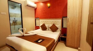 Hotelkamer met een bed, nachtkastje, airconditioning, wandlamp en een houten deur.