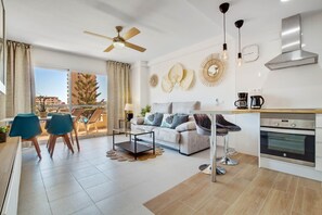 A modern apartment with a balcony, a kitchenette, and a living area with a sofa and chairs.