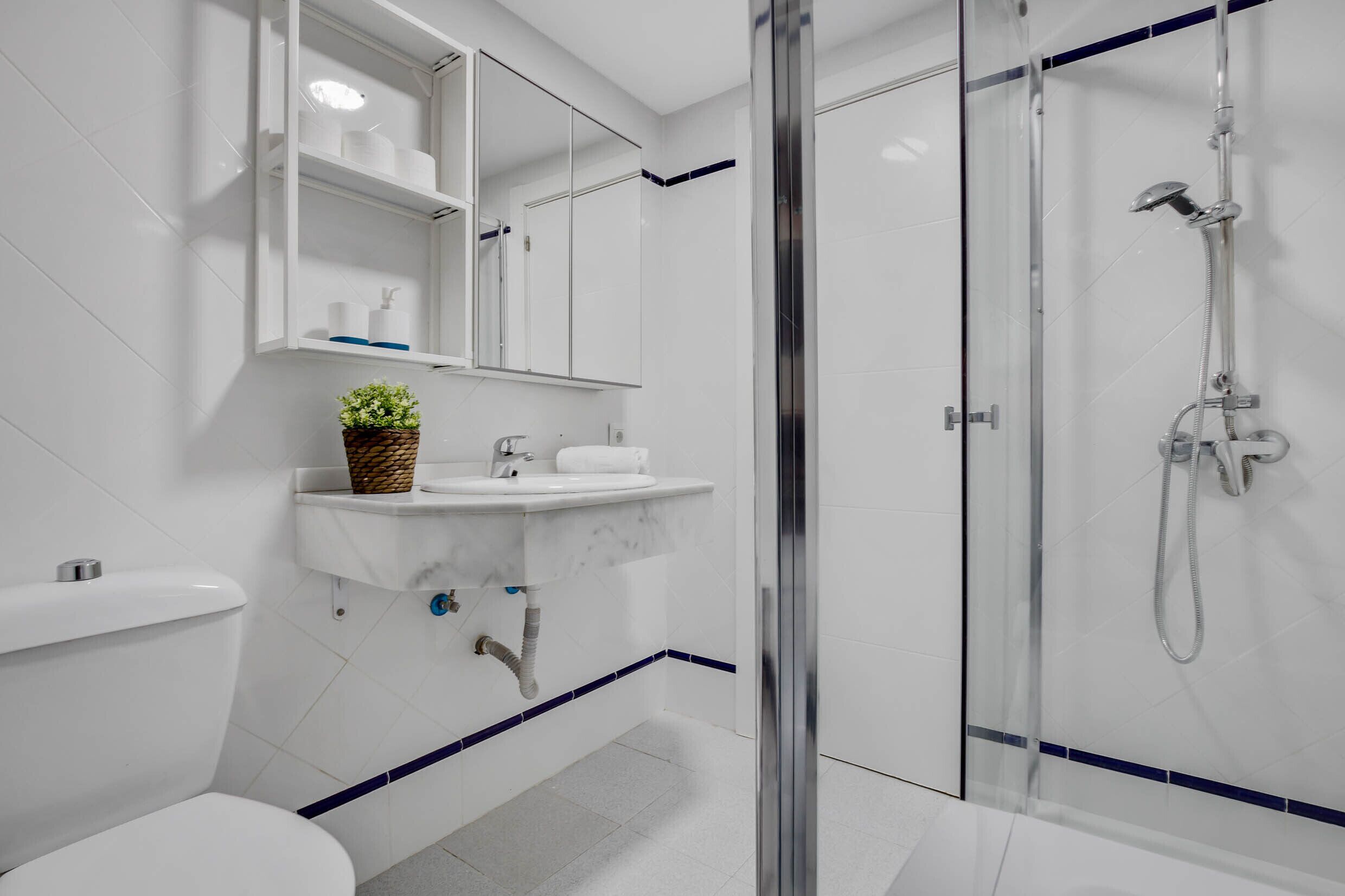 Uma casa de banho moderna com chuveiro em cabine de vidro, uma pia branca com bancada de mármore e sanita.