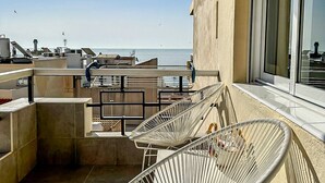A balcony with two white wicker chairs, a small table, and a view of the sea. - Casa Hugo - La Carihuela (Torremolinos)
