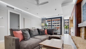 A modern living room with a sectional sofa, a coffee table, and a view of a multi-story building.