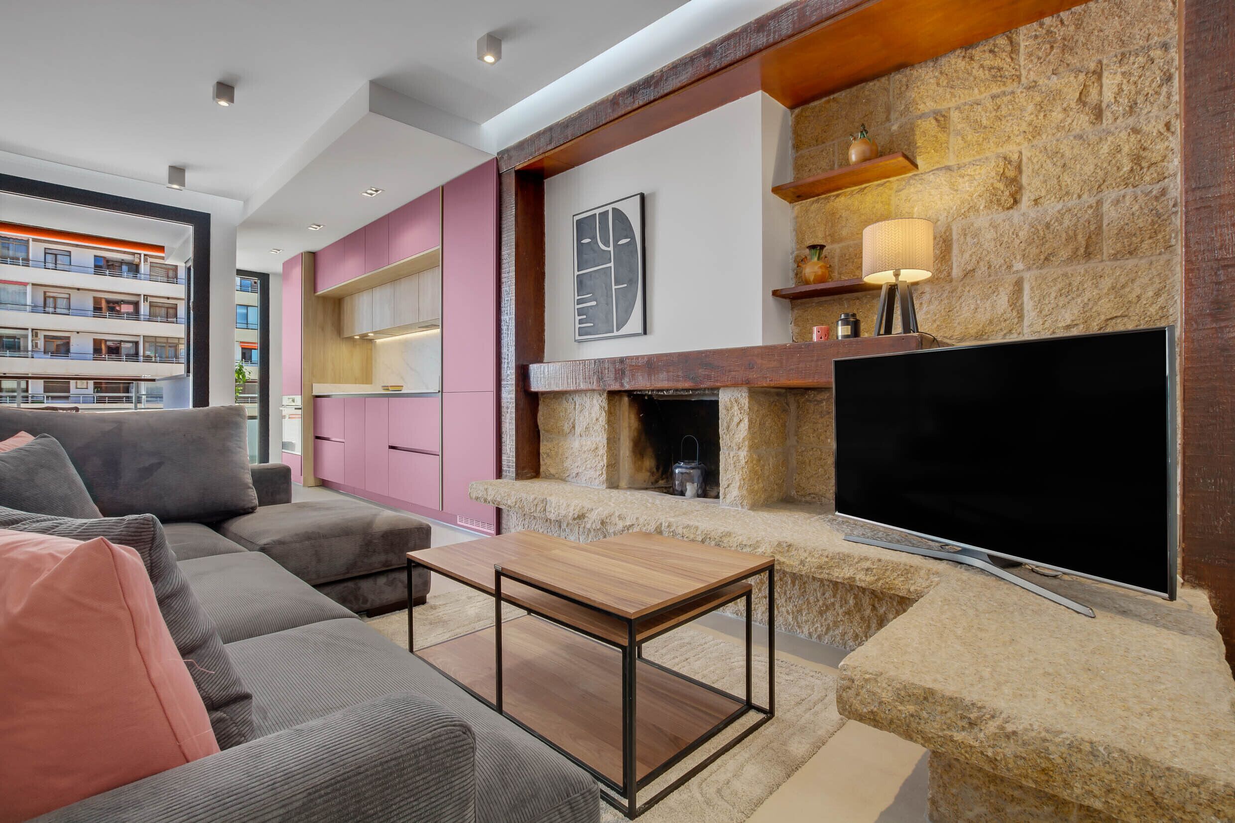 Uma sala de estar moderna com lareira de pedra, televisão de tela plana e sofá seccional.