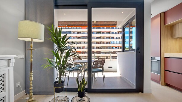A modern kitchen with a dining area, a large window, and a view of a multi-story building.