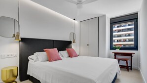 A modern bedroom with a large bed, bedside tables, and a window with a view of a building.