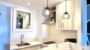 A modern kitchen with a marble countertop, stainless steel appliances, and pendant lighting. - Casa Lawrence - Sea Views (Torremolinos)