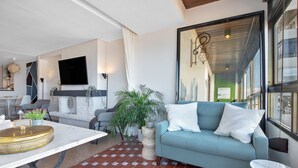 A modern living room with a sofa, a dining table, and a TV. - Casa Lawrence - Sea Views (Torremolinos)