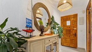 Un espace d’accueil doté d’une porte en bois, d’un grand miroir et d’un comptoir orné d’un vase et d’une statue.