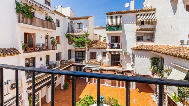 A narrow street with white buildings, balconies, and tiled roofs. - Casa Fandango - Pueblo Blanco (Torremolinos)