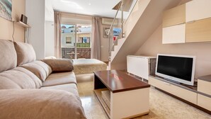 Een moderne woonkamer met een bank, televisie en een balkon met uitzicht.
