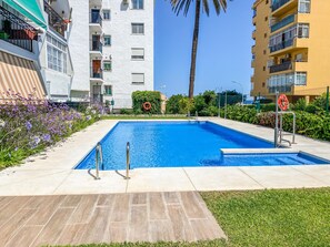 Une piscine équipée d’une bouée de sauvetage, entourée d’une pelouse et d’une terrasse en béton.