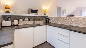 Una cocina moderna con armarios blancos, microondas, tostadora y cafetera.