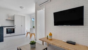 A modern kitchen with white cabinetry, a built-in oven, and a dining area with a wooden table and chairs. - Casa Lido - Front line beach (Torremolinos)