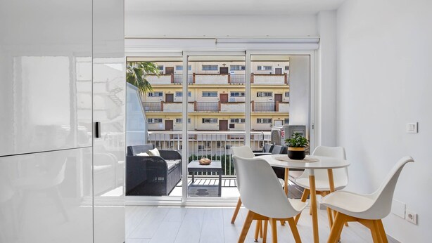 A modern apartment with a balcony, white furniture, and a view of a residential building. - Casa Lido - Front line beach (Torremolinos)
