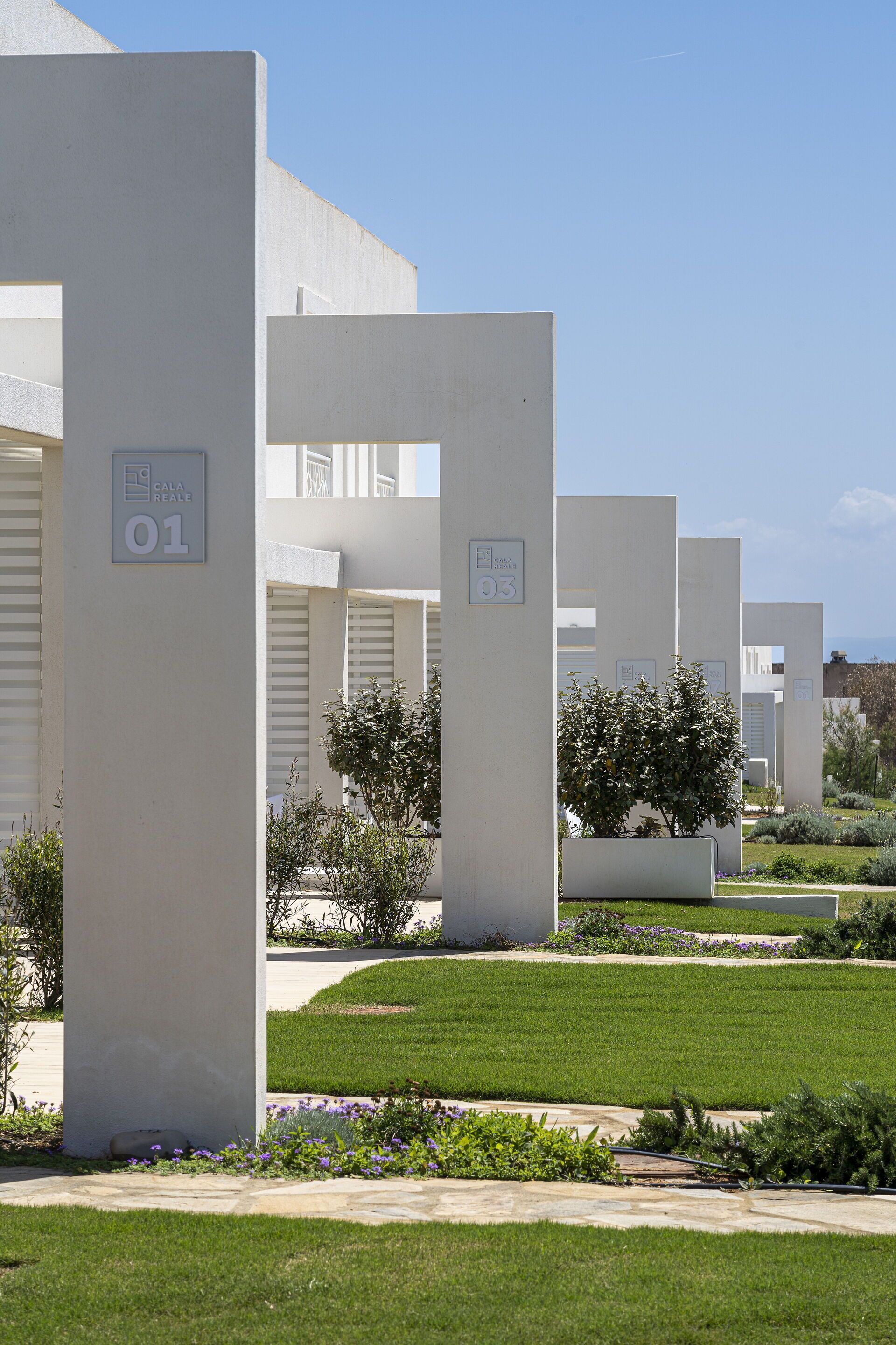 A row of modern, white buildings with numbered signs indicating unit numbers.