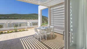 A balcony with a table and chairs, a view of the landscape, and a white railing.