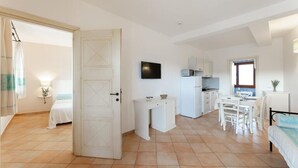A compact, well-lit room with a bed, a small kitchenette, a dining area, and a bathroom. - Onda Apartment Ac Wifi, Gallura (Portobello Di Gallura)