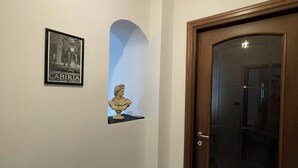 Un couloir orné d’un tableau encadré, d’un buste sculpté et d’une porte en bois.