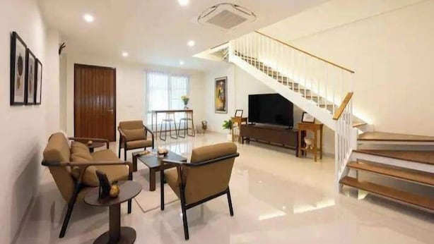 A modern living room with a staircase, a flat-screen TV, and a dining area. - Modern House CNX (Chiang Mai)
