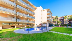 Un immeuble d’appartements moderne doté d’une piscine, de balcons et d’une pelouse bien entretenue.