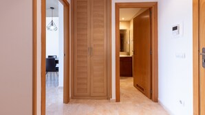 Un couloir avec des portes en bois, un coin repas avec des chaises et une salle de bain avec un lavabo et un miroir.