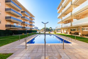A swimming pool with a metal pole in the center, surrounded by a paved walkway. - Maldivas I Apartment (La Pineda)