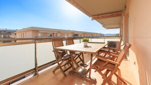 Un balcon avec une table et des chaises en bois, une plante en pot et un appareil de climatisation.