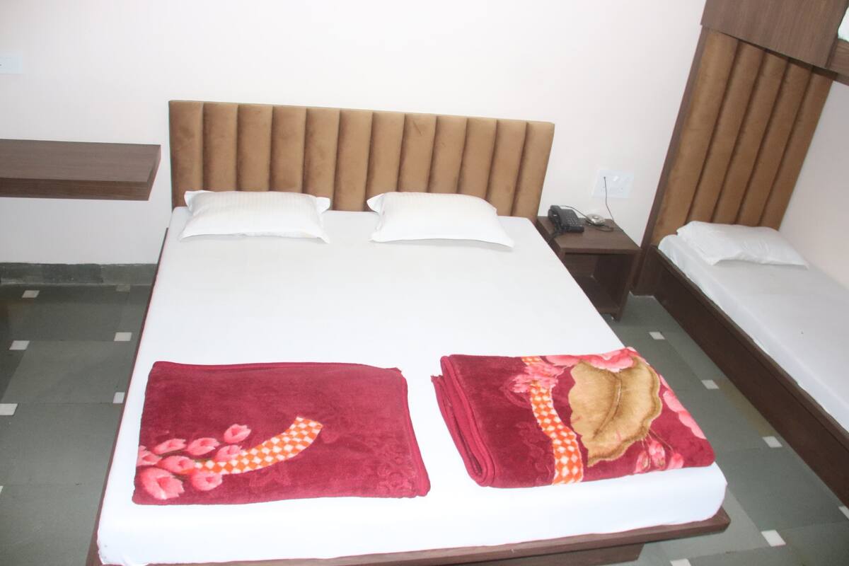 A neatly made bed with two pillows, a bedside table, and a small nightstand with a phone.
