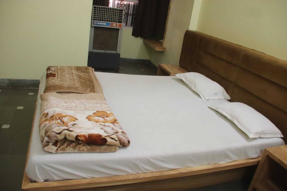 A bed with a floral bedspread and two pillows, a wooden headboard, and a small wooden nightstand.
