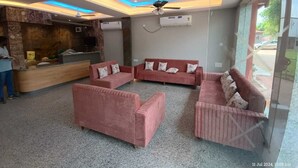 Un hall de hotel con una mesa de recepción, dos sofás, un ventilador de techo y un equipo de aire acondicionado.