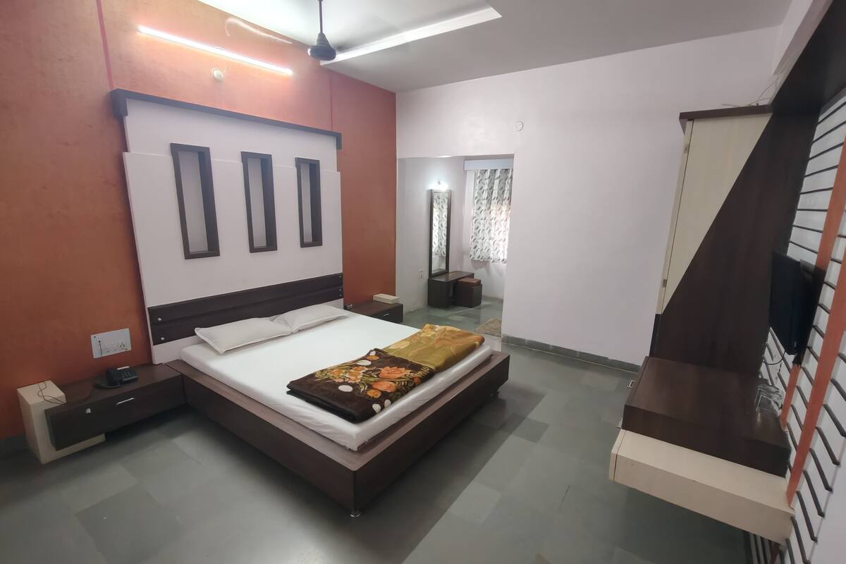 A modern bedroom with a bed, bedside tables, a ceiling fan, and a built-in TV shelf.